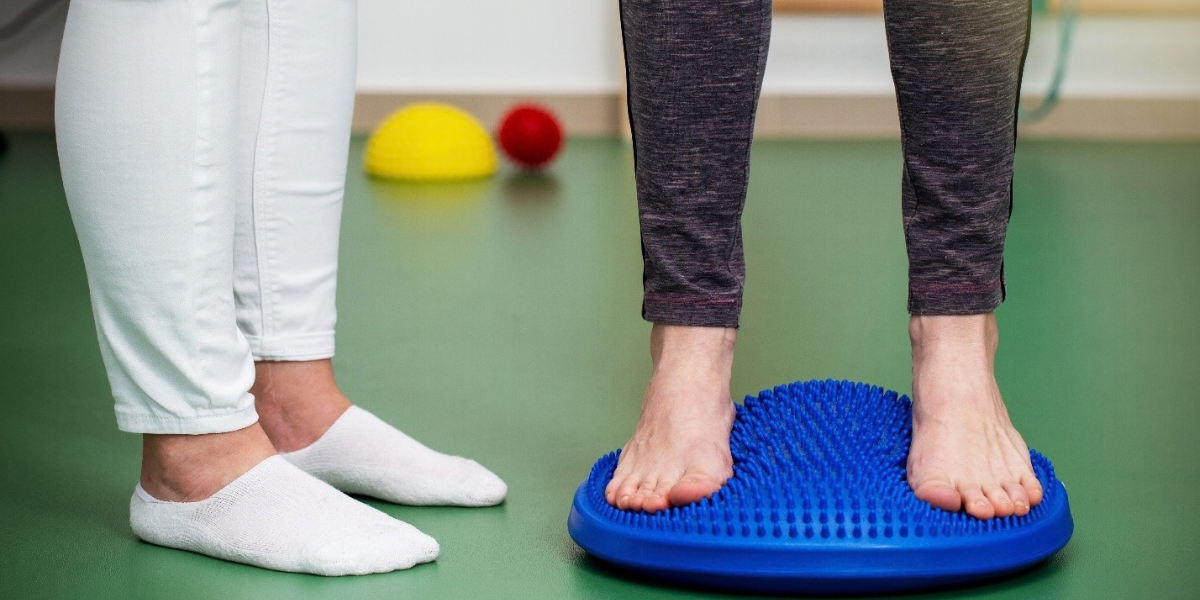 A woman stands upright on a blue ball, demonstrating balance and stability with her feet positioned on it.