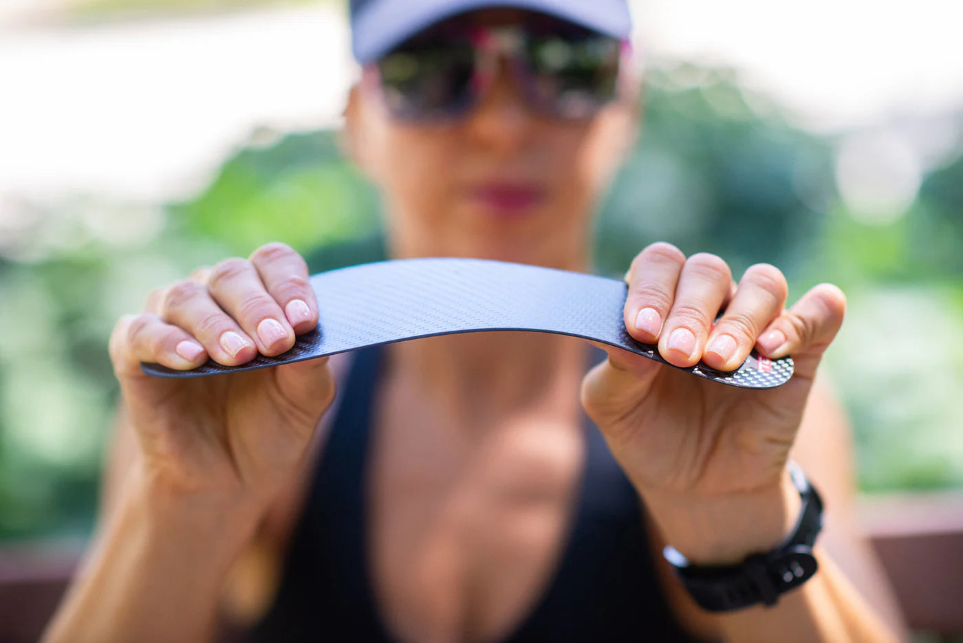 A close-up view of a carbon fiber insole being bent to showcase its exceptional flexibility. Despite its ultra-thin and lightweight design, the insole maintains high durability and resilience, offering optimal support without sacrificing comfort.